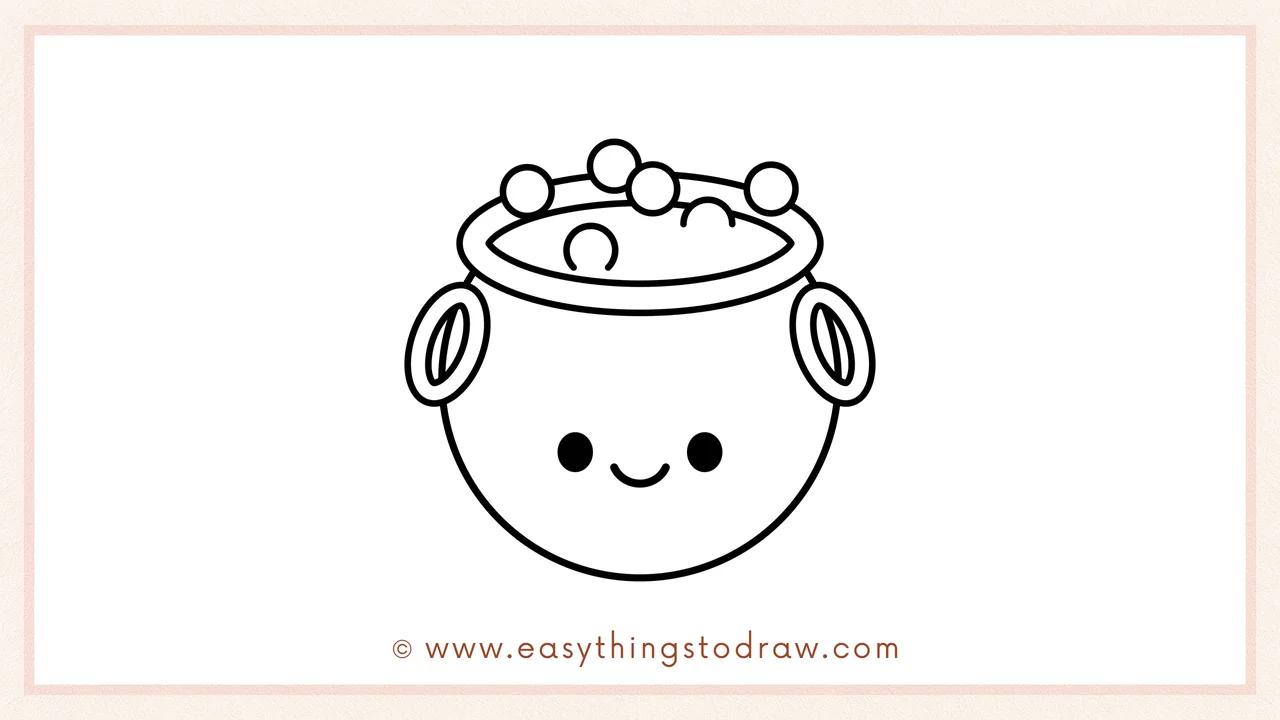Step 6 of simple cauldron drawing tutorial – Adding two dot eyes and a smiling mouth to give the cauldron a friendly face.
